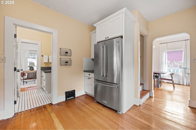 kitchen with high quality fridge, dark countertops, light wood-style flooring, and white cabinetry