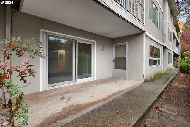 view of exterior entry with a balcony and a patio