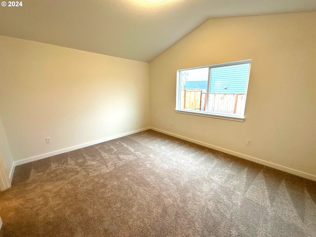 carpeted spare room featuring lofted ceiling