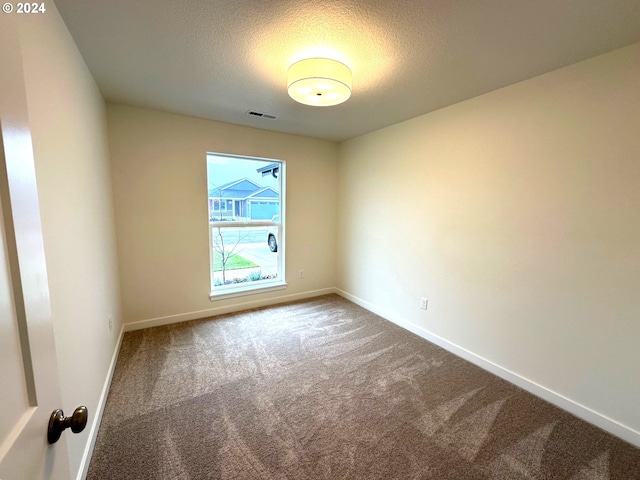 empty room with carpet floors and a textured ceiling