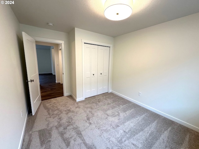 unfurnished bedroom featuring light carpet, a textured ceiling, and a closet