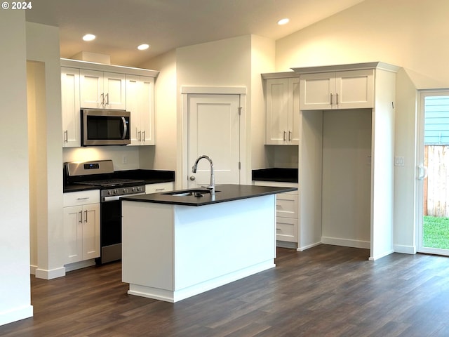 kitchen with appliances with stainless steel finishes, sink, white cabinets, dark wood-type flooring, and a center island with sink