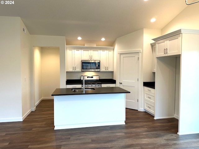 kitchen featuring dark wood-type flooring, white cabinets, stainless steel appliances, and an island with sink