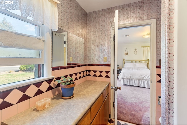 bathroom with vanity, a wealth of natural light, and tile walls