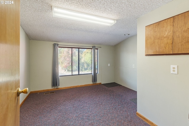 carpeted empty room featuring a textured ceiling