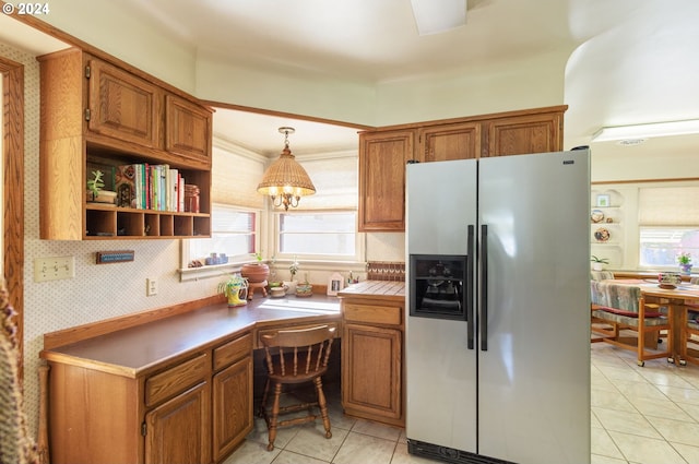 kitchen featuring light tile patterned flooring, hanging light fixtures, stainless steel fridge with ice dispenser, and a healthy amount of sunlight