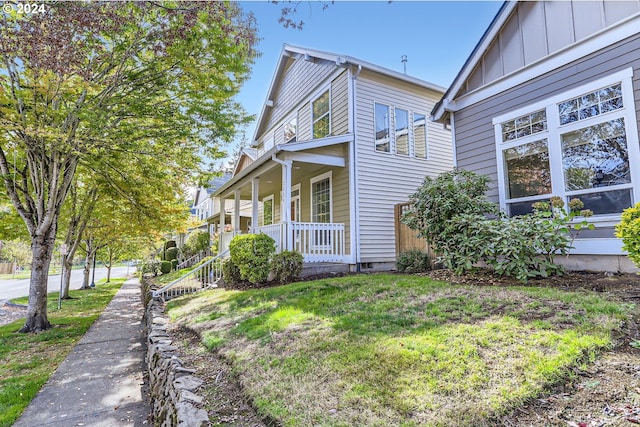 view of side of home with a porch and a lawn