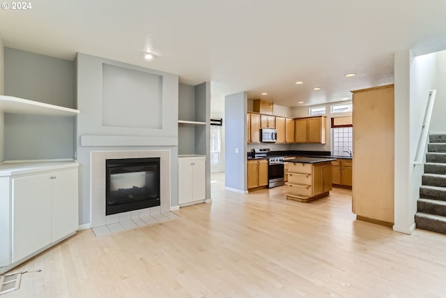 kitchen featuring a kitchen island, light hardwood / wood-style flooring, a tile fireplace, sink, and appliances with stainless steel finishes