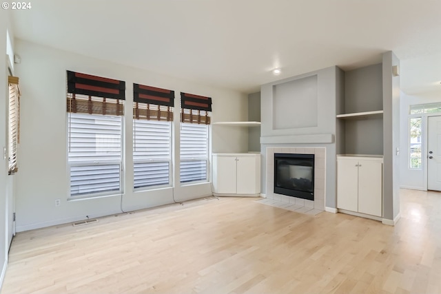 unfurnished living room with light hardwood / wood-style flooring and a tile fireplace