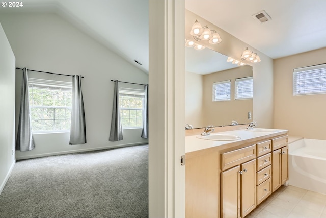 bathroom with vanity, a tub, tile patterned floors, and vaulted ceiling