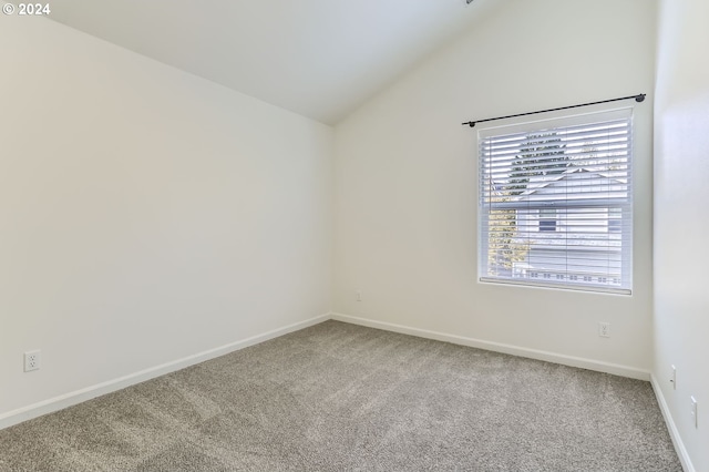 carpeted spare room featuring vaulted ceiling