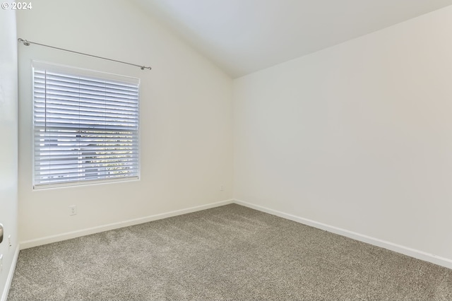 carpeted spare room with vaulted ceiling