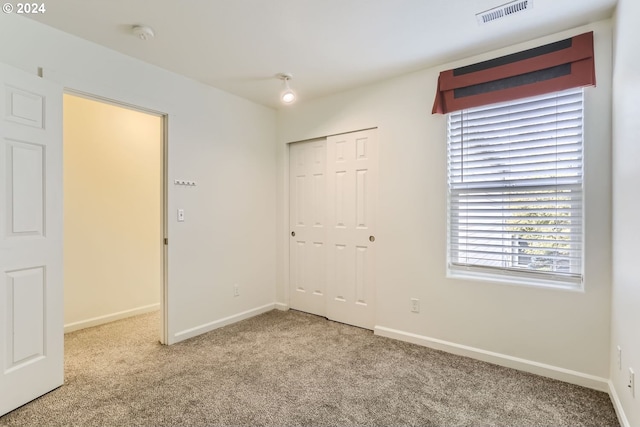 unfurnished bedroom featuring light carpet and a closet