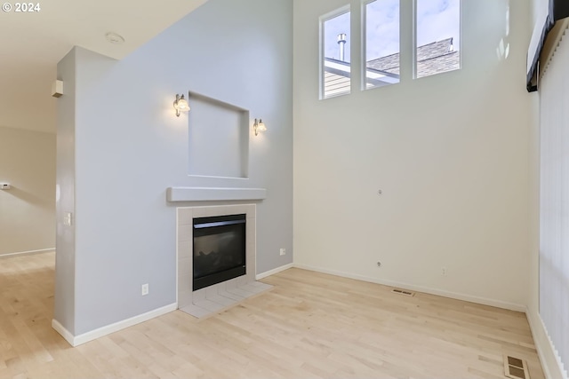 unfurnished living room with light hardwood / wood-style flooring and a tile fireplace