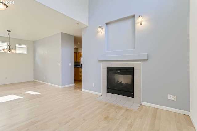 unfurnished living room featuring a fireplace, a chandelier, and light wood-type flooring