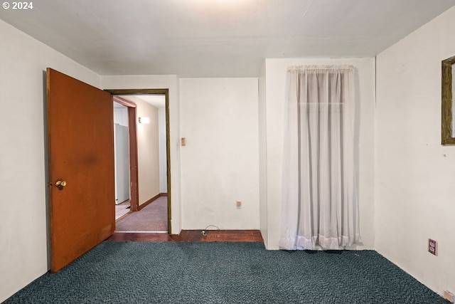 unfurnished room featuring dark colored carpet