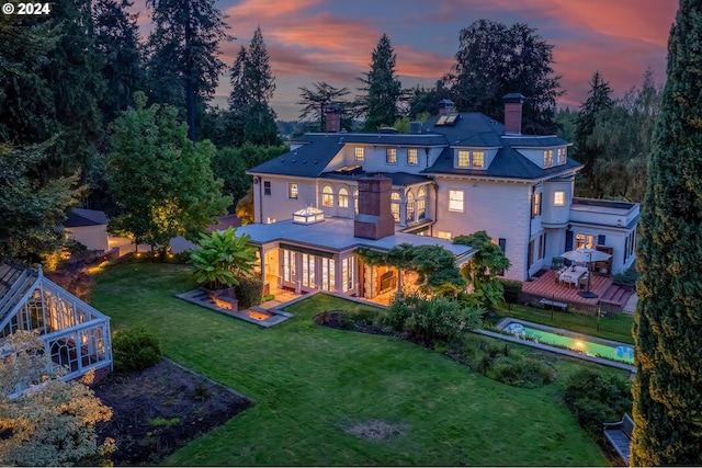 back house at dusk with a deck and a yard