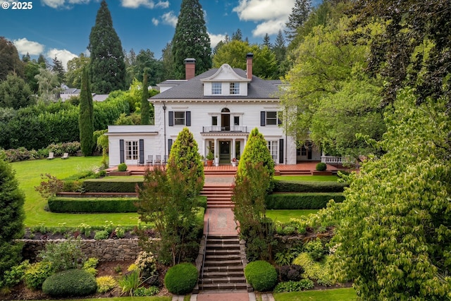 back of house with a balcony and a yard