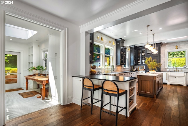 kitchen with dark hardwood / wood-style floors, a center island, pendant lighting, and a skylight