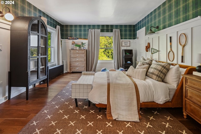 bedroom featuring radiator heating unit, multiple windows, and dark hardwood / wood-style flooring