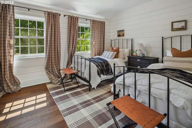 bedroom with lofted ceiling, wood walls, and dark hardwood / wood-style floors