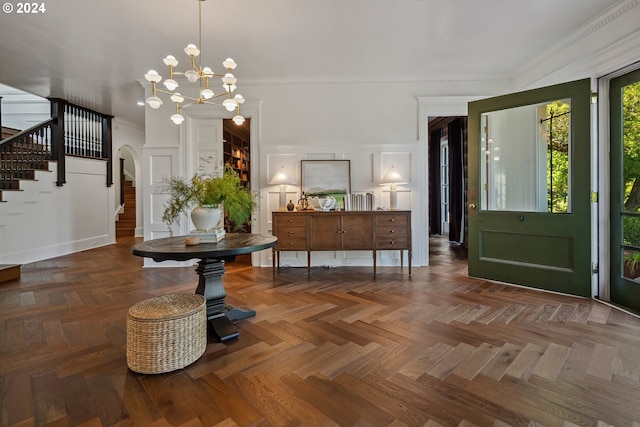 foyer entrance featuring crown molding, dark parquet floors, and a notable chandelier