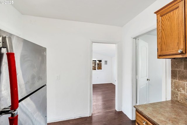 hallway with vaulted ceiling and dark wood-type flooring