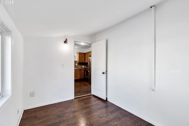 spare room featuring lofted ceiling and dark wood-type flooring