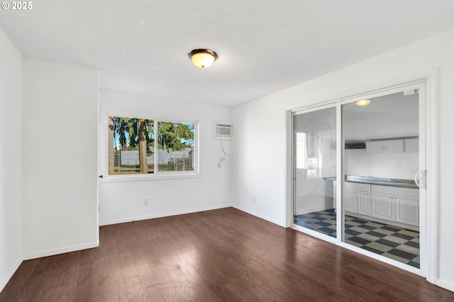 empty room featuring a wall mounted air conditioner and dark hardwood / wood-style floors