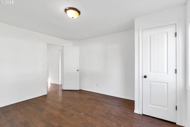 empty room featuring a textured ceiling and dark wood-type flooring