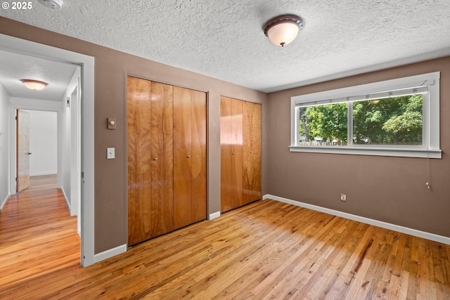 18021 Tualata Ave, Lake Oswego, OR 97035 - unfurnished bedroom featuring two closets, hardwood / wood-style floors, and a textured ceiling