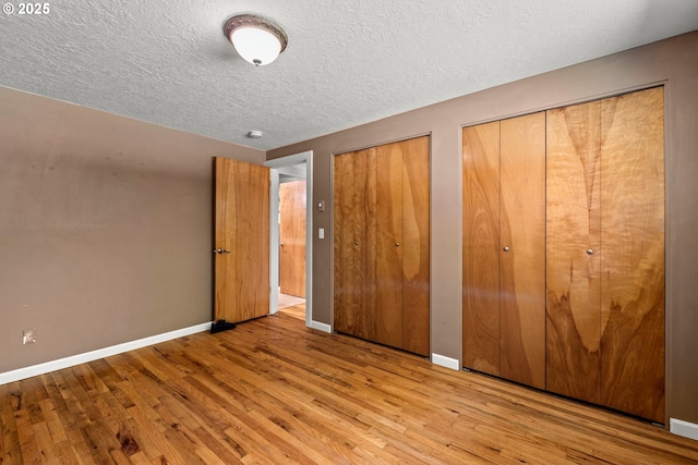 18021 Tualata Ave, Lake Oswego, OR 97035 - unfurnished bedroom featuring multiple closets, wood finished floors, and a textured ceiling