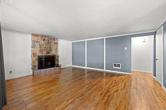 18021 Tualata Ave, Lake Oswego, OR 97035 - unfurnished living room with a textured ceiling, hardwood / wood-style flooring, and a stone fireplace