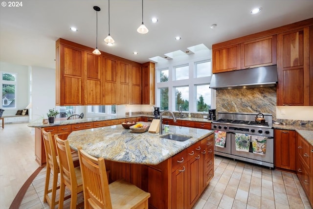 kitchen featuring sink, double oven range, a kitchen island with sink, and a breakfast bar area