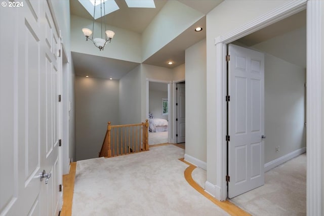 hallway with a skylight, light carpet, and a chandelier