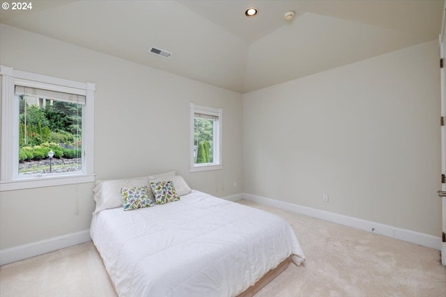 bedroom with light carpet and lofted ceiling