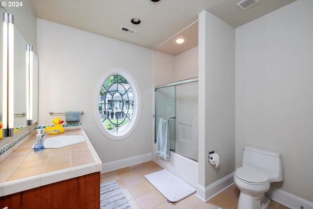 full bathroom featuring tile patterned floors, toilet, vanity, and combined bath / shower with glass door