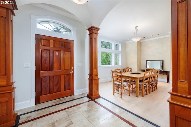 foyer entrance featuring a healthy amount of sunlight, ornate columns, and crown molding