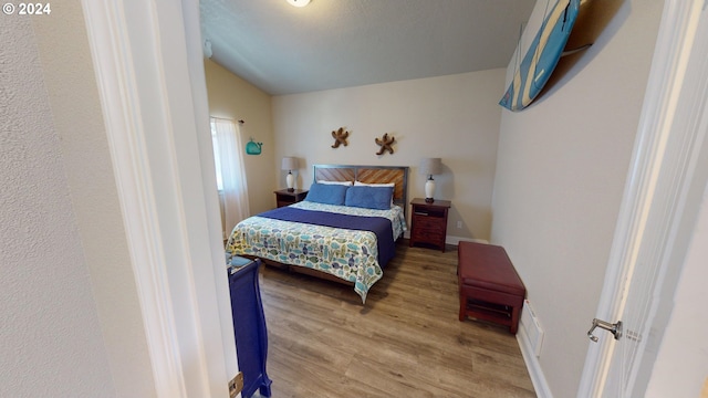 bedroom featuring hardwood / wood-style floors and vaulted ceiling