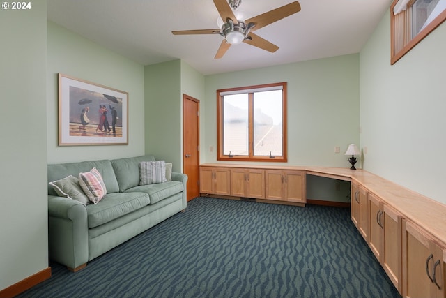 carpeted office space featuring built in desk and ceiling fan