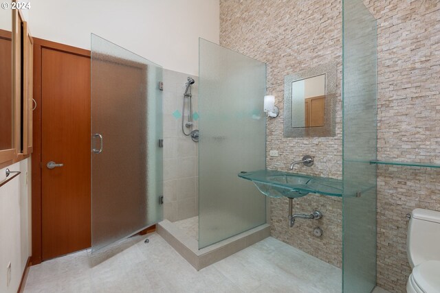 bathroom featuring a shower with door, sink, tile patterned flooring, and toilet