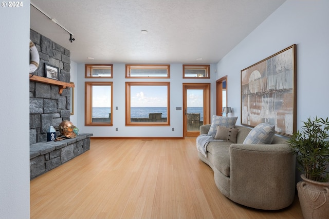 living room featuring light hardwood / wood-style flooring, a fireplace, and a textured ceiling