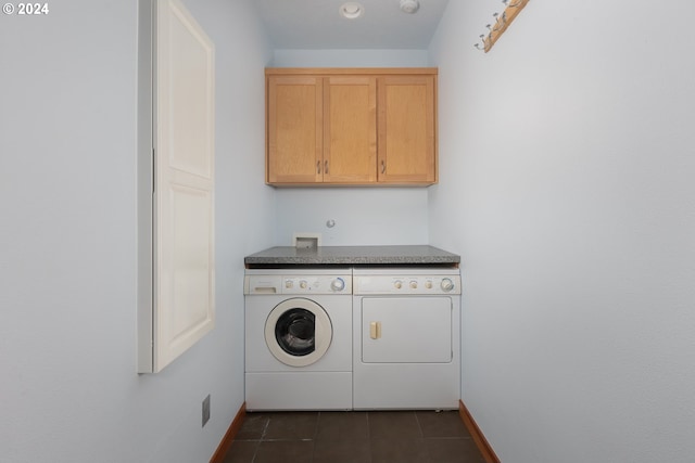 clothes washing area featuring cabinets, washing machine and clothes dryer, and dark tile patterned flooring