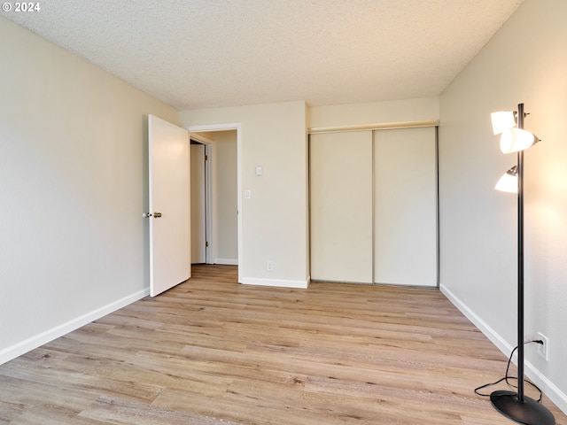 unfurnished bedroom featuring light hardwood / wood-style floors, a closet, and a textured ceiling