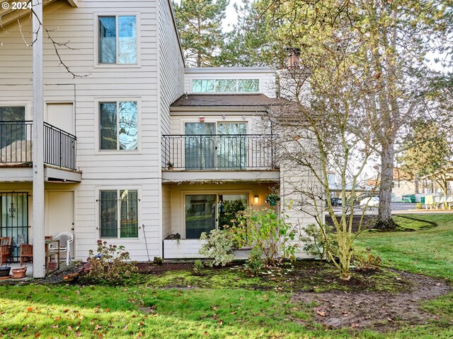 rear view of property with a balcony and a lawn