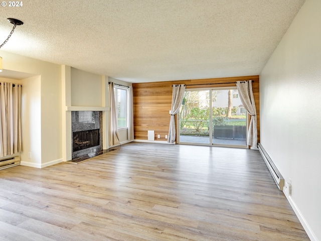 unfurnished living room with light wood-type flooring, a wealth of natural light, a premium fireplace, and baseboard heating