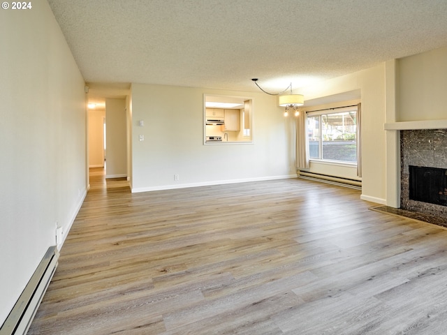 unfurnished living room with a tiled fireplace, light wood-type flooring, a textured ceiling, and baseboard heating