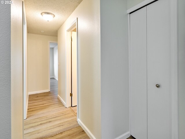 hallway featuring light hardwood / wood-style flooring and a textured ceiling