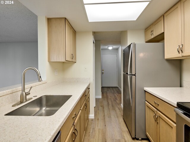 kitchen with sink, stainless steel electric range, light brown cabinets, a textured ceiling, and light wood-type flooring