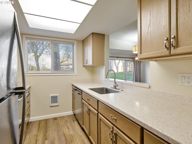 kitchen featuring light brown cabinetry, sink, light wood-type flooring, and appliances with stainless steel finishes